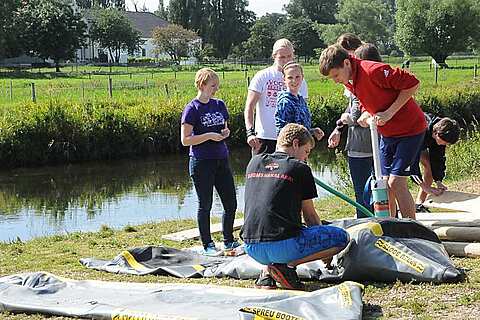 Jugendlliche pumpen Schwimmkoerper auf beim Flossbau Event | mit GeccoTours-TeamEvents.com